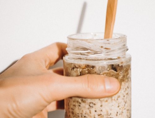 a person holding a jar of food with a wooden spoon in it