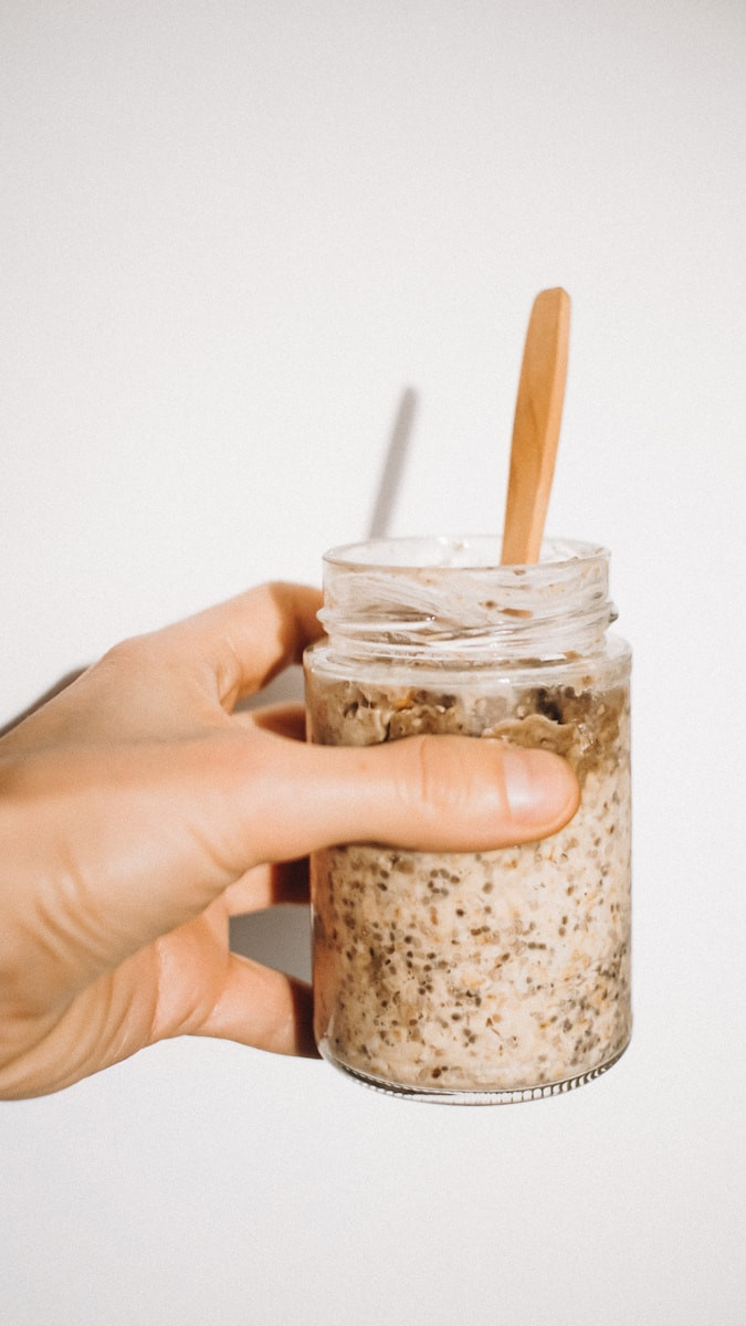 a person holding a jar of food with a wooden spoon in it