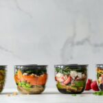 four clear plastic bowls with vegetables